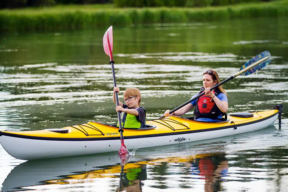 A mother paddling with his son on a tandem kayak