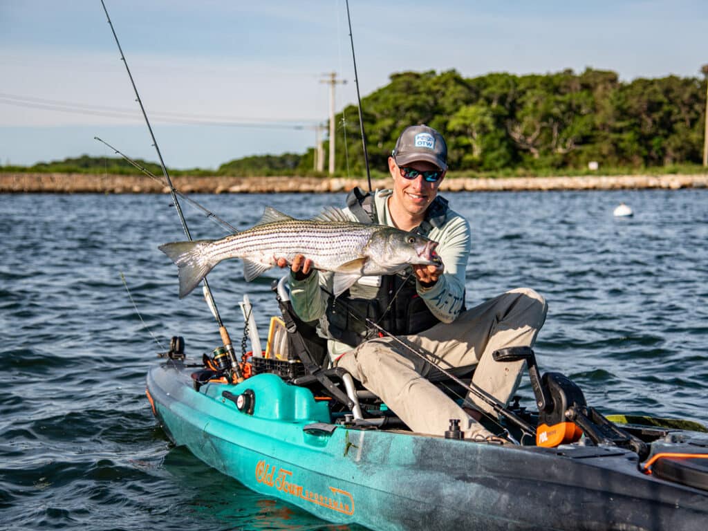 A person holding a heavy fish sititng on a kayak