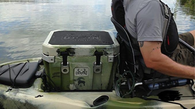 A person sitting on a kayak with a kayak cooler on back