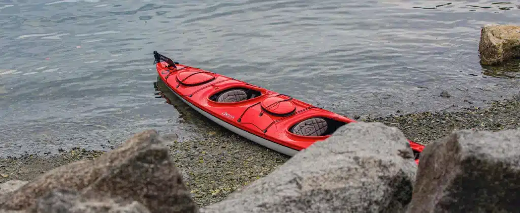 A red tandem kayak sitting at the shore