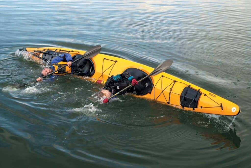 Two people rolling in a tandem kayak at the sea with the kayak tilted