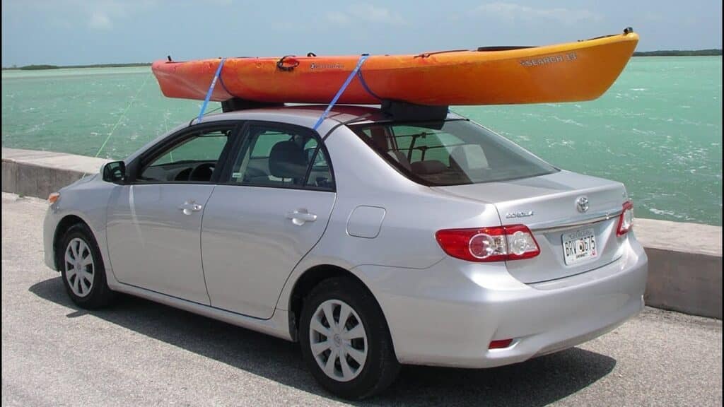 a car is carrying a kayak at sea side