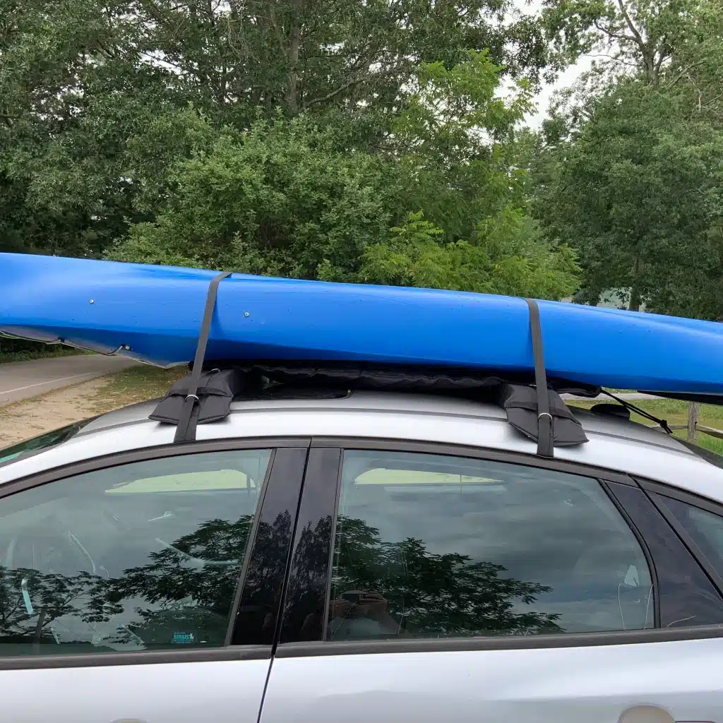 a car is carrying a kayak with the help of roof rack