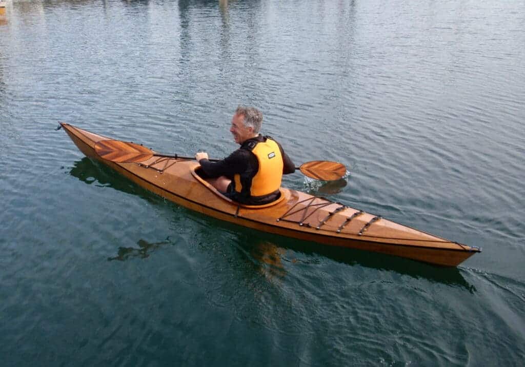 old man kayaking in wooden kayak