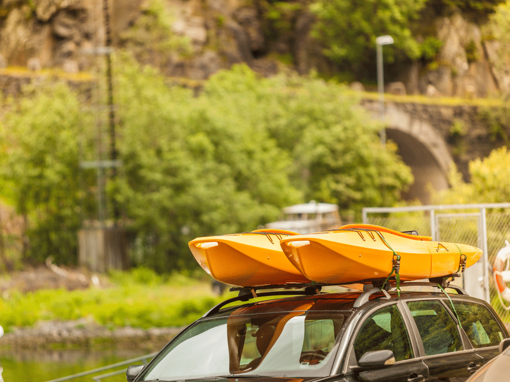 Car with kayak yellow canoe on top roof ready to transportation