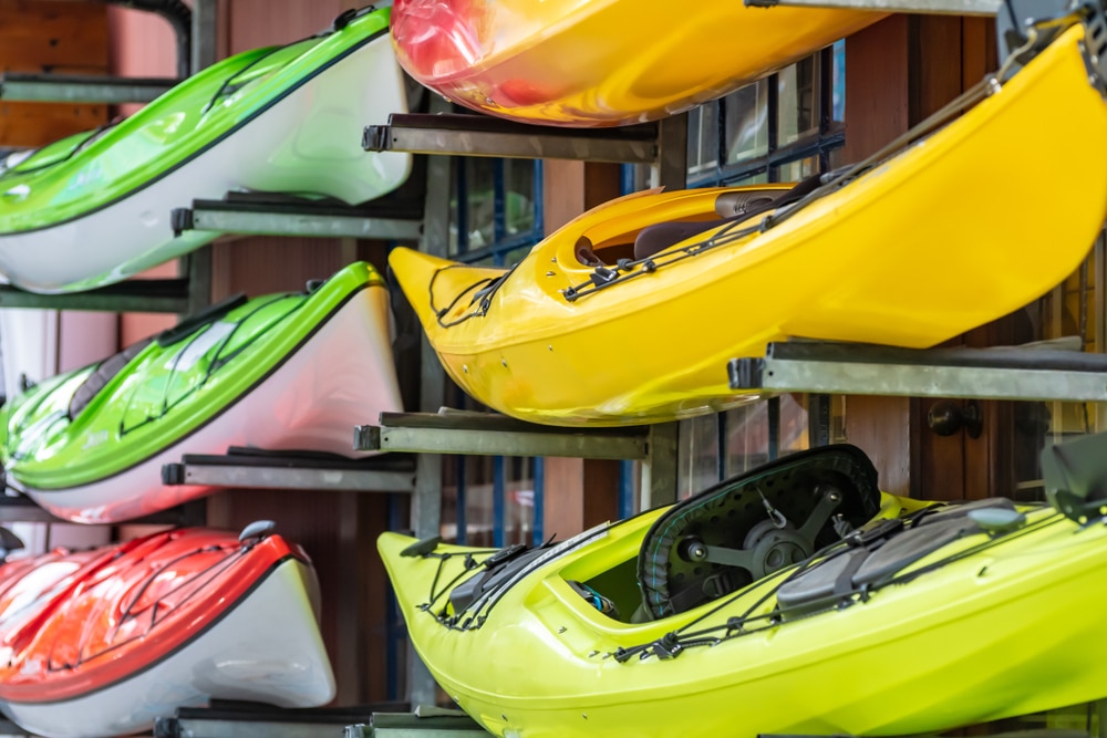 Colorful Brightly Colored Kayaks For Rental Stacked Outside A Water
