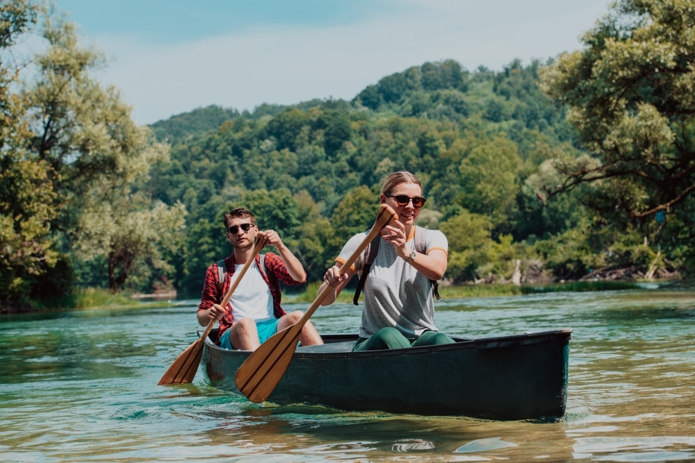 Couple Adventurous Explorer Friends Are Canoeing In A Wild River