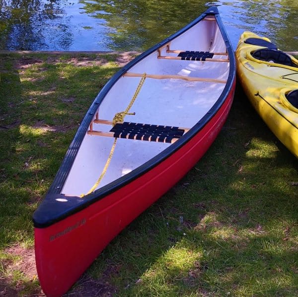 a full image of a kayak with half image of canoe standing near water