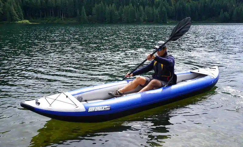 a kayaker kayaking on water with paddle in hand