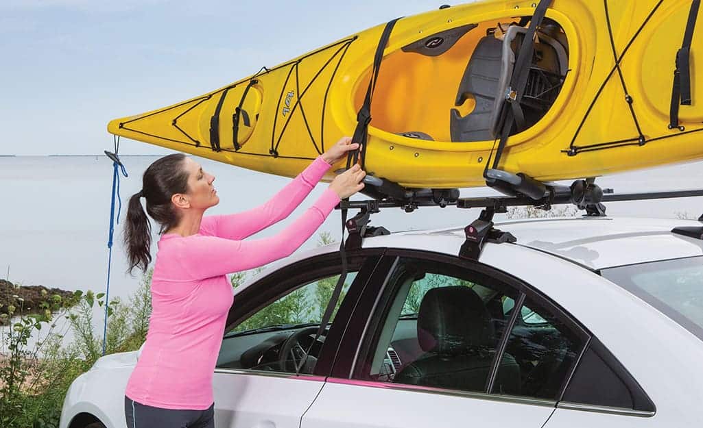 a lady installing kayak on roof rack