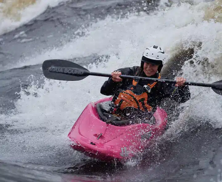 a lady kayaking in a white water kayak