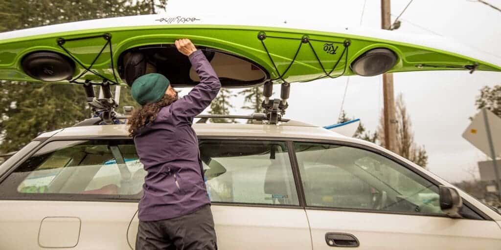 a man fitting a kayak on car roof rack