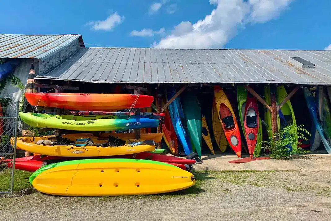 different types of kayaks stored in a room and placed outside