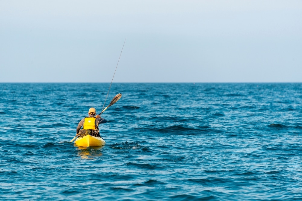 Fisherman Kayaker Paddling Canoe Out To Sea