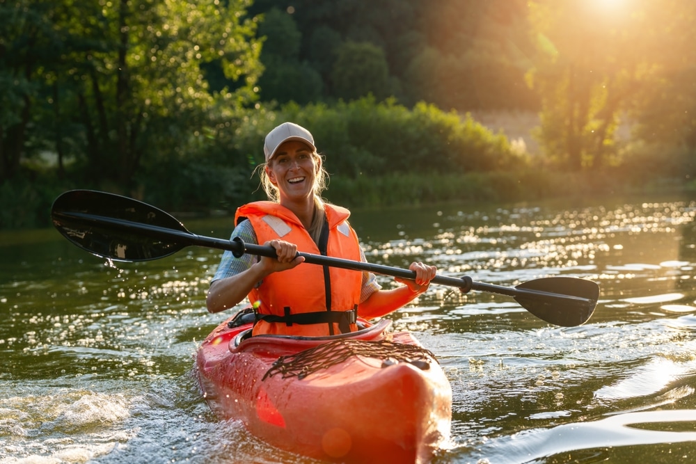 Woman Joyfully Paddling A Red Kayak In A River During