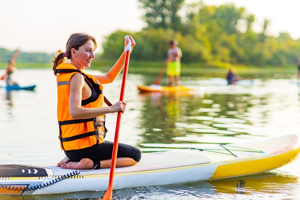 Woman In Life Jacket Sit At Sub Board At River