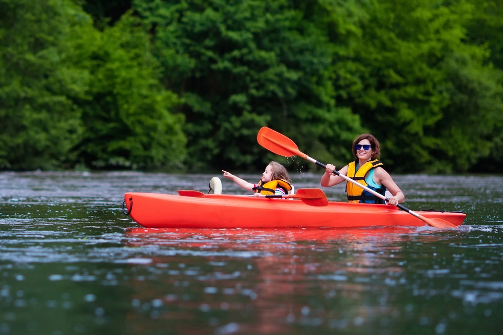 Mother and child paddling in kayak in a river