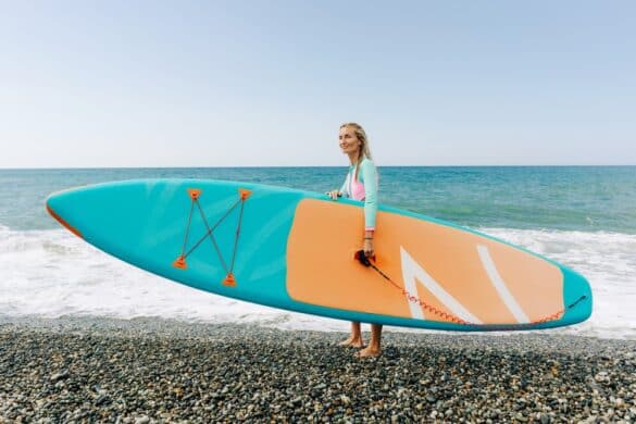 Young Athletic Blonde Woman Stands On The Beach And Holds