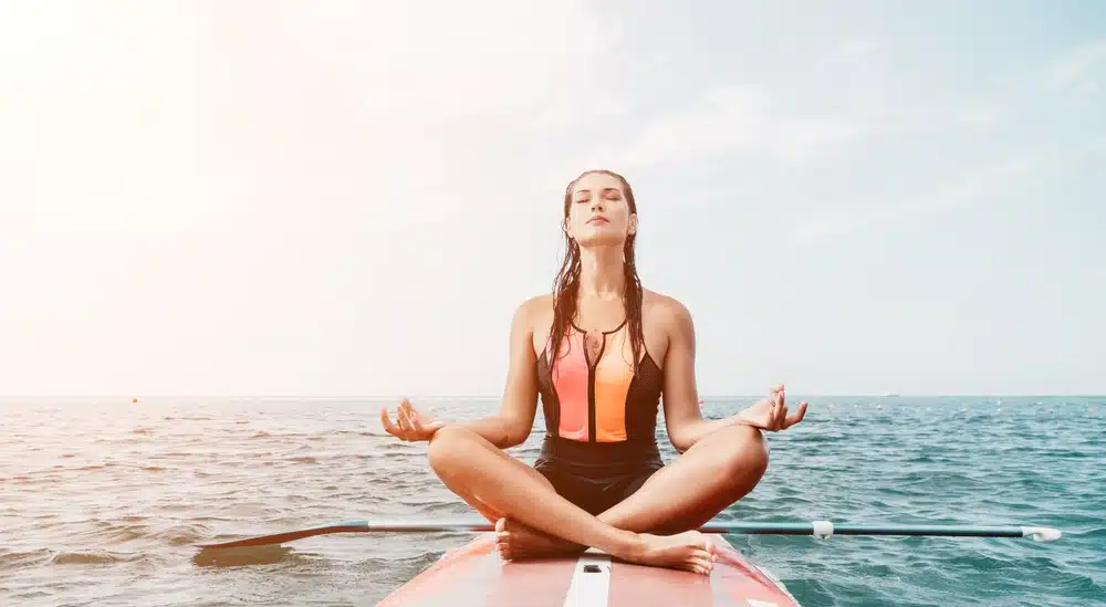 Woman sup yoga Happy young sporty woman practising yoga pilates on paddle sup surfboard